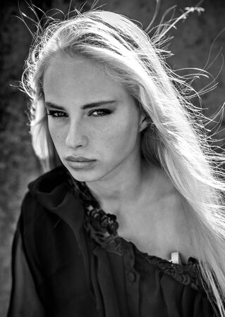 Close up portrait of beautiful blonde woman in black clothes posing outsideの写真素材