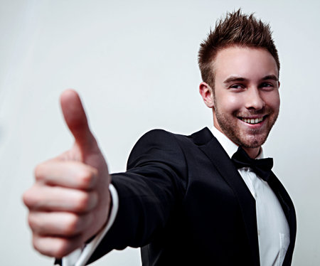 Portrait of beautiful handsome man in black classic suit poses on white background.の写真素材