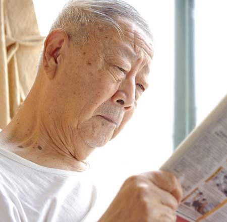 a senior man is reading newspaperの写真素材