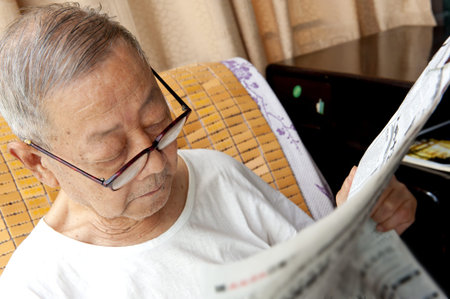 a senior man is reading newspaper