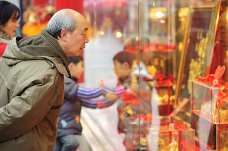 CHENGDU - FEB 7: A man stop to look in the window of a gold shop on a busy pedestrian shopping street in downtown during chinese new year on Feb 7, 2011 in Chengdu, China.のeditorial素材