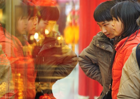 CHENGDU - FEB 7: A woman and man stop to look in the window of a gold shop on a busy pedestrian shopping street in downtown during chinese new year on Feb 7, 2011 in Chengdu, China.のeditorial素材
