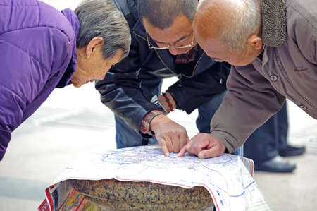 CHENGDU - FEB 7: A man to search the way on the map on a busy pedestrian shopping street in downtown during chinese new year on Feb 7, 2011 in Chengdu, China.のeditorial素材