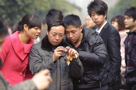 CHENGDU - FEB 7: A man looking at his pictures just taken on a busy pedestrian shopping street in downtown during chinese new year on Feb 7, 2011 in Chengdu, China.のeditorial素材