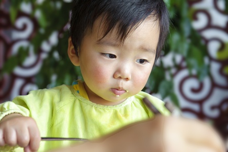 a cute baby is eating in restaurantの写真素材