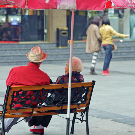 CHENGDU - FEB 7: An old couple resting on a chair on a busy pedestrian shopping street in downtown during chinese new year on Feb 7, 2011 in Chengdu, China.のeditorial素材