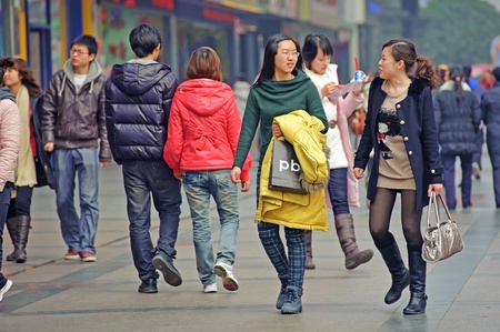 CHENGDU - FEB 7: Two girls pass through a busy pedestrian shopping street in downtown during chinese new year on Feb 7, 2011 in Chengdu, China.のeditorial素材