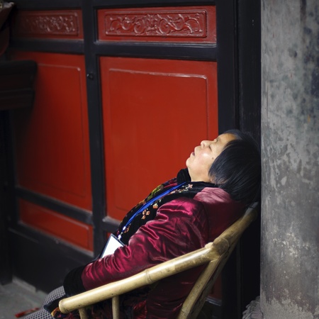 CHENGDU - FEB 14: Tired old woman sleeping on a chair in the temple
 on Feb 14, 2010 in Chengdu, China. のeditorial素材