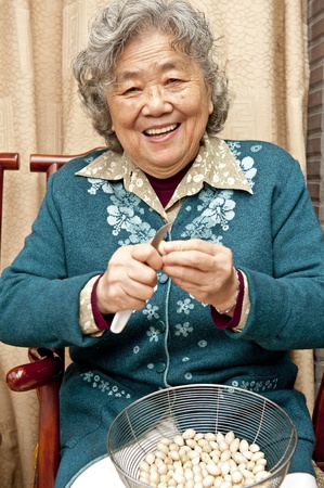 Grandmother peeling nut fruit の写真素材