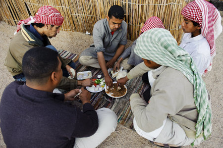 HURGHADA - JAN 30: Bedouin men enjoying traditional arabic breakfast beside a thatch house.Jan 30,2013 in Hurghada,Egypt.のeditorial素材