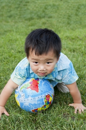 baby holding the earth model on the grass の写真素材