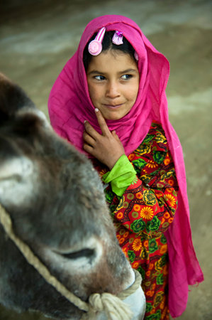 HURGHADA - JAN 29: arab girl pulling a donkey and looking at photographer with a smile.Jan 29,2013 in Hurghada,Egypt.のeditorial素材