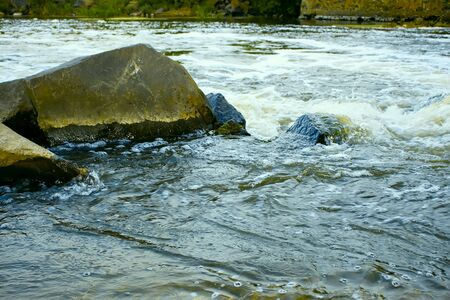 Rapid fast flow of water among the stones on shallow riverの写真素材