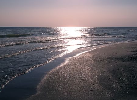 Sandy seashore. Sunlight reflected in the water at sunset     の写真素材