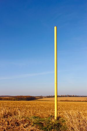 Yellow high iron pillar in the middle of autumn fields. Under ground pipeline laidの写真素材