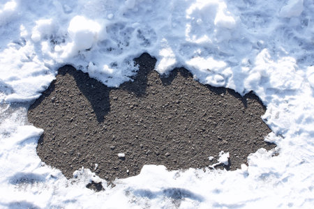 Fragment of the asphalt surface between snowbanksの写真素材