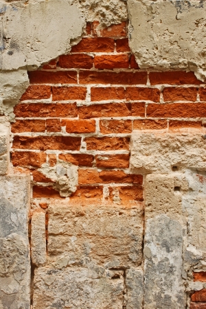 Fragment of old brick masonry on a foundation with destroyed stucco close-upの写真素材