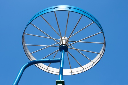 Metal painted detail in the form of a bicycle wheel on the blue sky backgroundの写真素材