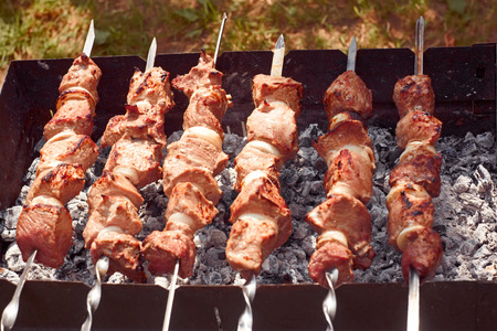 Shashlik (shish kebab) prepared on the metal skewers outdoors in summertimeの写真素材