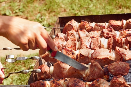 Preparation of meat slices on the metal skewers close up outdoors in summerの写真素材