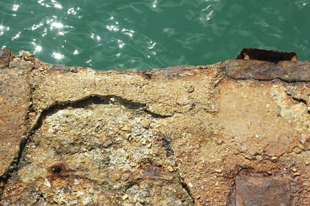 Detail of old reinforced concrete pier over the water in a bright sunlightの写真素材