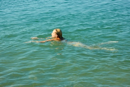 Teenage girl swimming in sea water in warm sunny weatherの写真素材