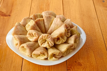 Stuffed cabbage rolls in the white dish on the wet wooden tableの写真素材