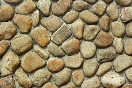 Fragment of old wall with decorative trim from rounded large stone boulders