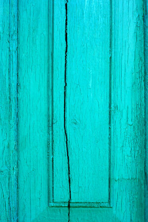 Fragment of old cracked wooden board painted in turquoise colorの写真素材