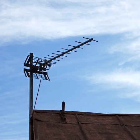 Television antenna over old metal roof on the sky backgroundの写真素材