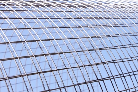Metal grid of white alloy shines in bright sunlight on the blue sky backgroundの写真素材