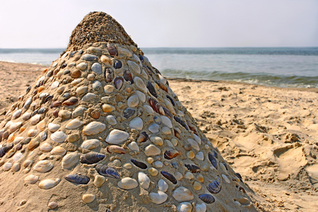 Sandy pyramid with many shells mosaic on a sea beach, close-upの写真素材
