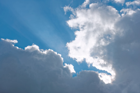 Heaven, cloudscape of light white and gray clouds against blue sky with sun beamsの写真素材