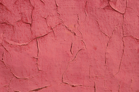 Old shelled and cracked red painted wall in sunlight as a backgroundの写真素材