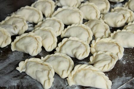 Dumplings with potatoes on the dark kitchen board. Dumplings with potatoes (or cottage cheese, cabbage, cherries, etc.) is a traditional Ukrainian dish is also known as Varenyky or Vareniksの写真素材