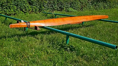 Parked wooden canoe inverted upside down to dry on a metal tubular support on the green foliage background in serene summer sunny dayの写真素材