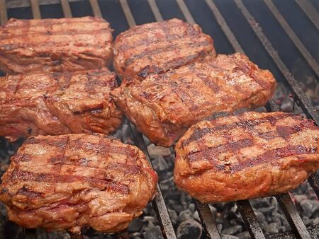 Large pieces of meat are roasted on metal bars over hot charcoal, close-upの写真素材