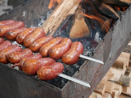 Sausages on still skewers roasted on charcoalの写真素材