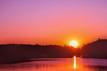 Sunset over lake. Setting sun on the cloudless sky. View reservoir at evening. Artistic pattern editedの写真素材
