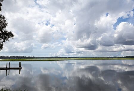 Dramatic Puffy White Clouds reflected in May River, Bluffton, South Carolina.  Dock on left.の写真素材
