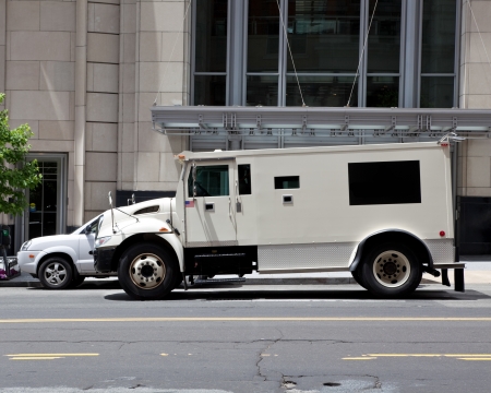 Side view of gray armored double parked on street making a cash pickup.