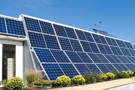 Exterior modern solar home with a row of photovoltaic solar panels and a solar hot water heater to...