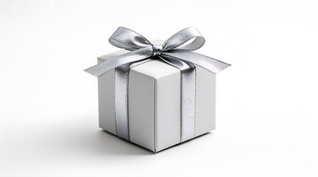 Gift box elegan berwarna putih dengan pita perak mengilap di atas latar belakang putih bersih.の素材