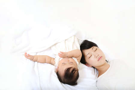 Mother and daughter sleeping on white bed, top view. Space for textの写真素材
