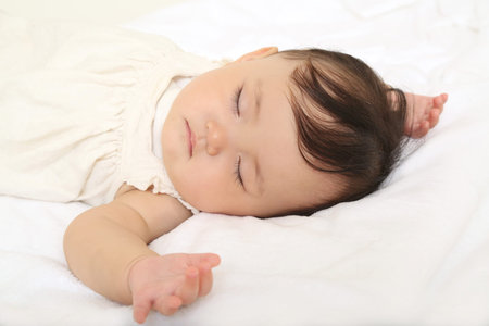 Baby girl taking a nap on white sheets