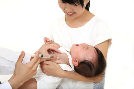 Baby girl being injected on a white background. Childcare, illness, and immunization imagesの写真素材