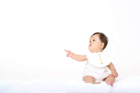 Baby girl sitting and pointing on white backgroundの写真素材