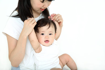 Mother's upper body playing with baby girl in front of white background