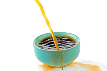 Over pouring tea on a cup on white backgroundの写真素材