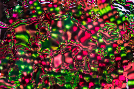 A beautiful horizontal bright colored blured texture of water drops and reflection of rainbow transparent hydrogel balls, water beads in green and red color looks fantastic on the wet surface of mirrorの写真素材